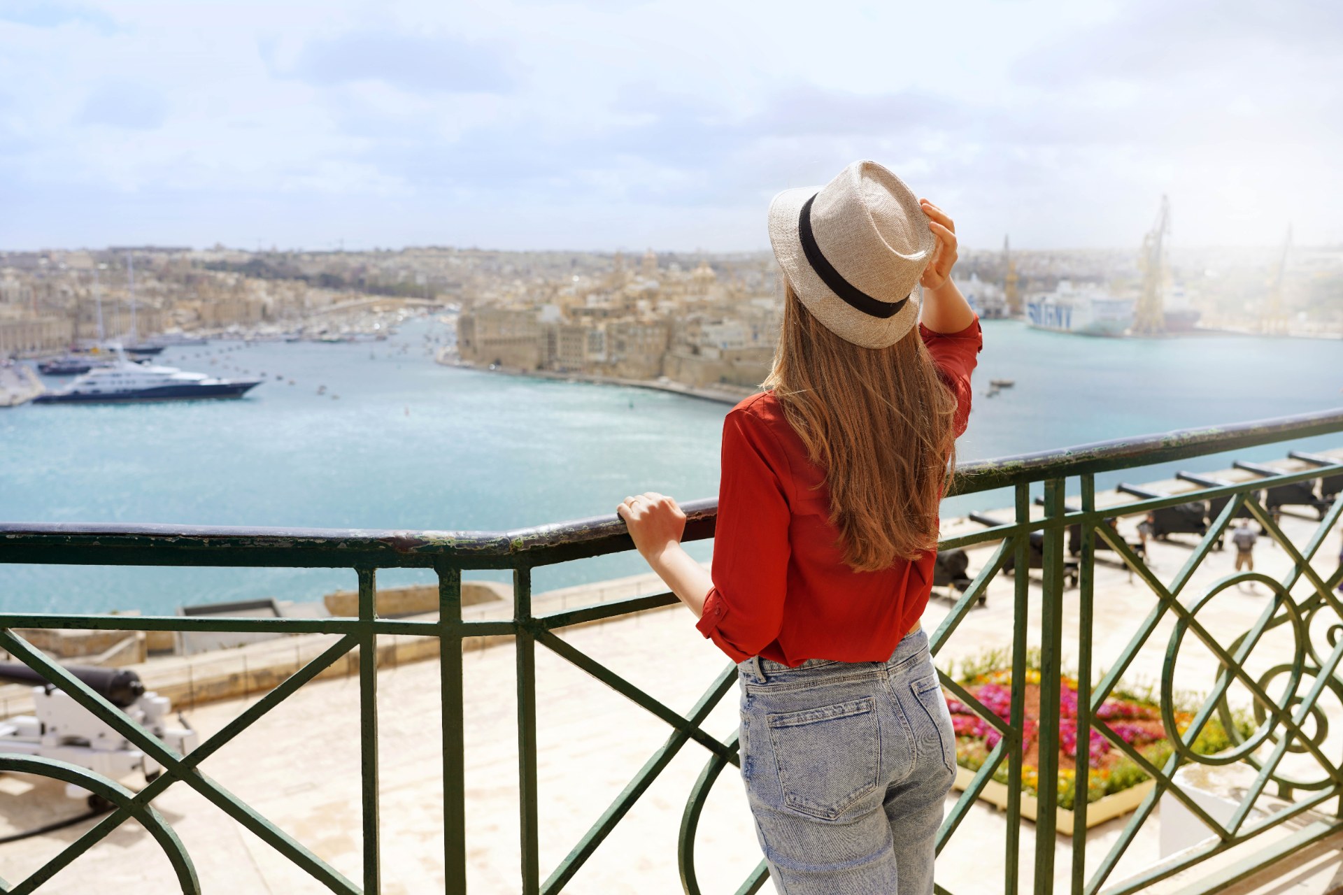 Young woman enjoying the view of the Three Cities from Upper Barrakka Gardens in Valletta